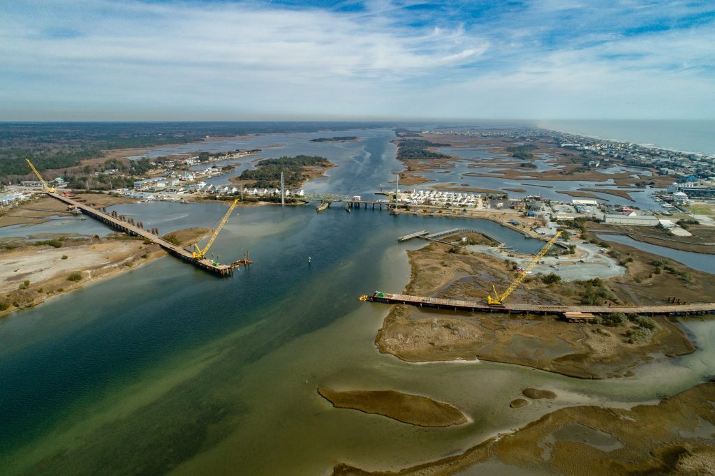 A temporary trestle allowed crane access for pile installation, starting from each end of the future bridge’s footprint and meeting in the middle. Visible in the background is the Surf City swing-span bridge that will be decommissioned after the new bridge is opened.
